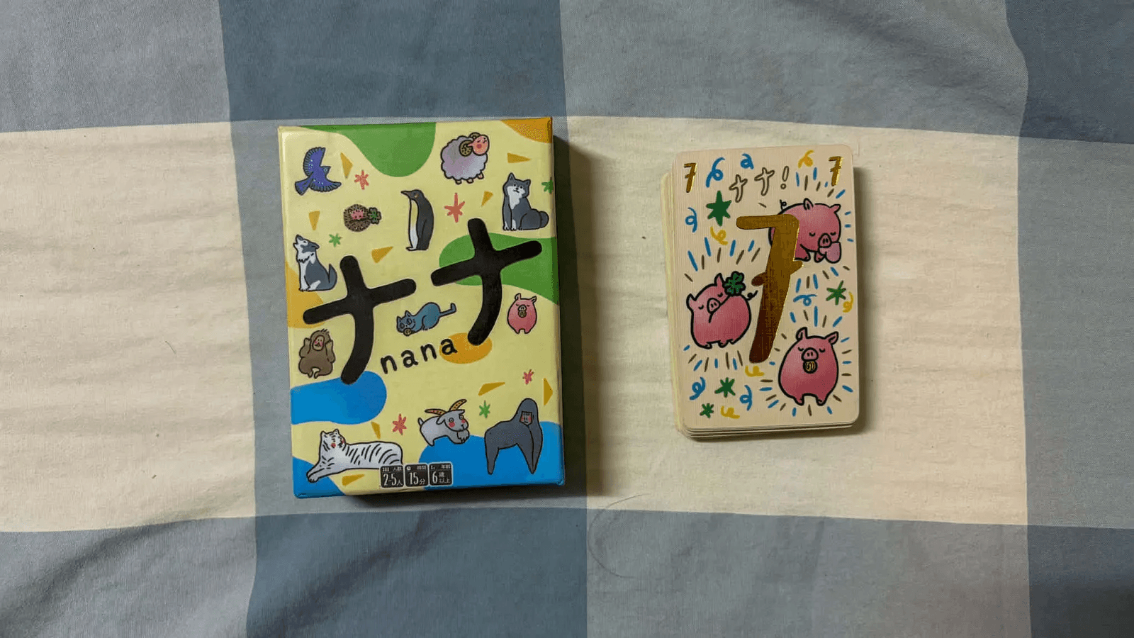 The Nana (ナナ / Trio) box beside a stack of cards crowned by the golden seven.