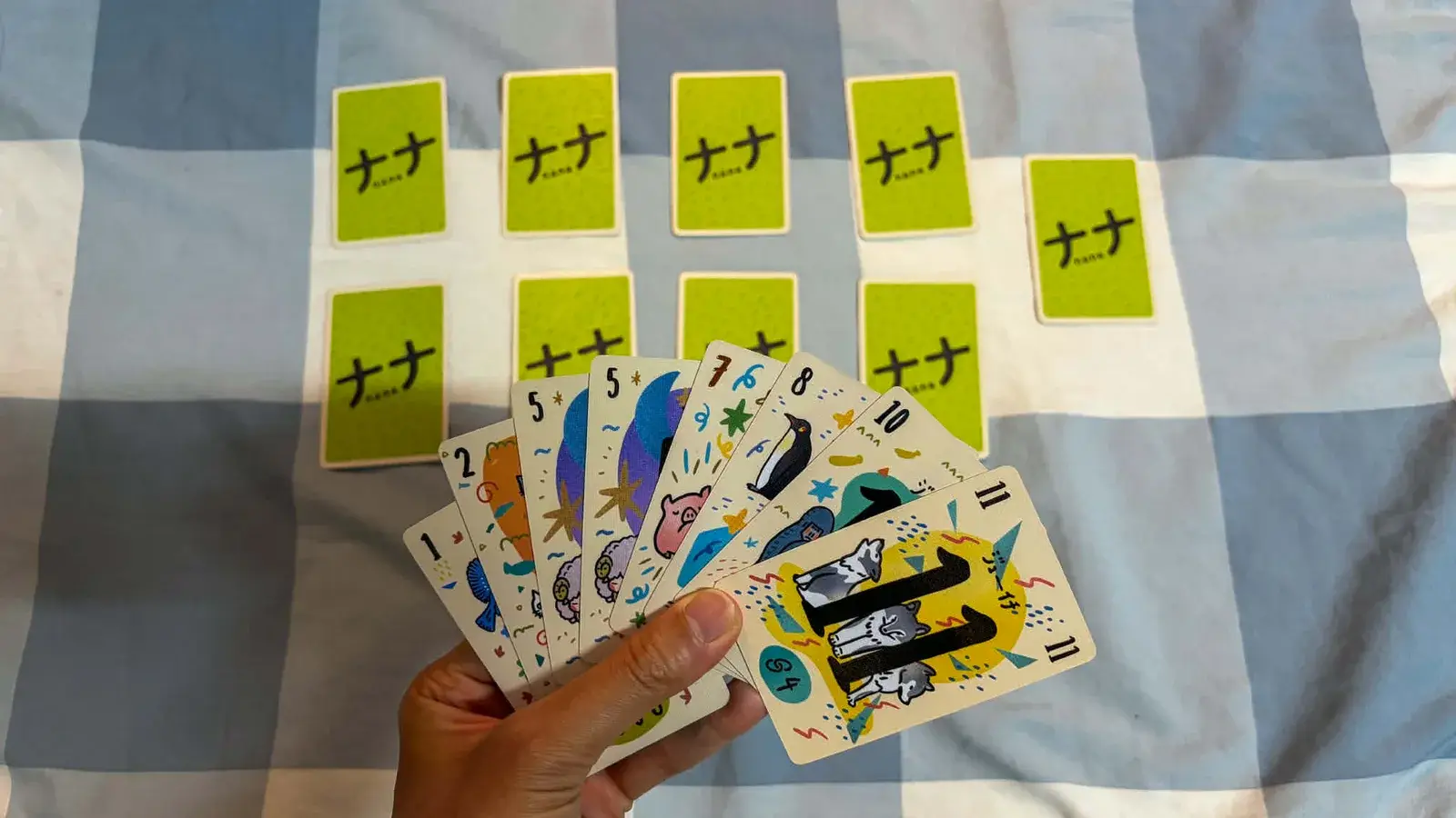 A face-down grid of green-backed cards in the middle, with a fanned hand sorted low to high held in front.